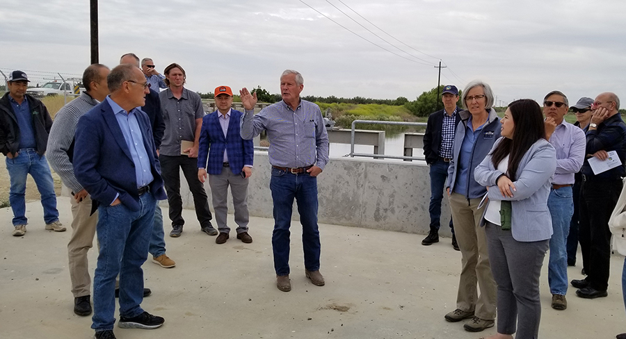Terranova Ranch manager Don Cameron, center, leads a tour of the McMullin On-Farm Flood Capture and Recharge Project in May 2019. California Water Commission Chair Armando Quintero, foreground left, and Commissioner Maria Herrera, foreground right, took part in the tour.