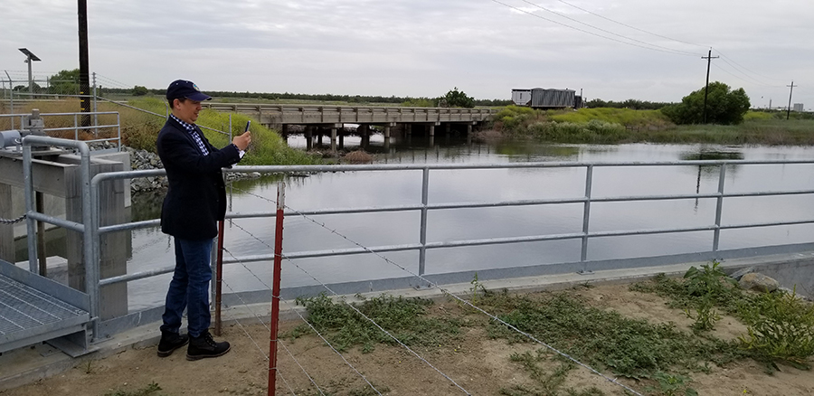 Art Hinojosa, manager of the Department of Water Resources Division of Integrated Water Management, tours the McMullin On-Farm Flood Capture and Recharge Project on the Kings River. In the background are the head gates that divert floodwaters from the river into the project’s canal system.