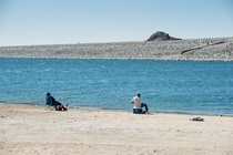 Two men fish from the shore of Lake Perris