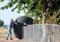 An installer rolls a 1500 gallon potable water tank into place at a residence in Glenn County, California, where wells have run dry.