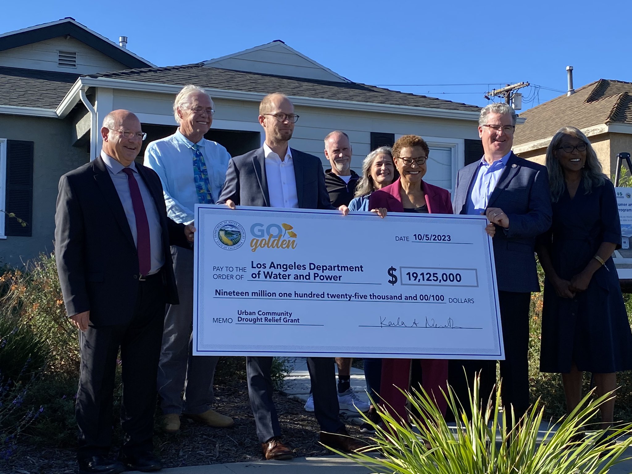 Los Angeles Mayor Karen Bass, Deputy Director Integrated Watershed Management Kristopher Tjernell, and others present a Go Golden check at a house that received funds to replace their lawn with drought-resistant plants.
